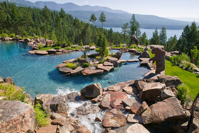 Foto de piscina con fuente natural rústica extra grande a medida en patio trasero con adoquines de piedra natural