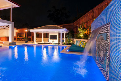 Imagen de piscina con fuente alargada clásica renovada grande a medida en patio trasero con adoquines de piedra natural