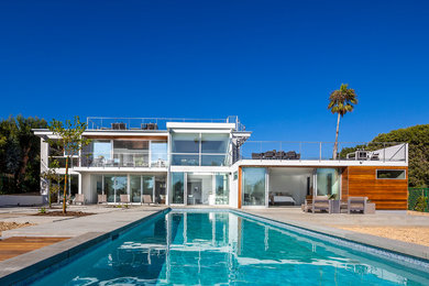 Immagine di una piscina monocorsia design rettangolare dietro casa con pavimentazioni in cemento