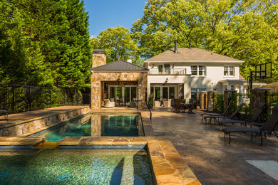 Foto de piscina de estilo americano de tamaño medio en patio trasero con adoquines de piedra natural