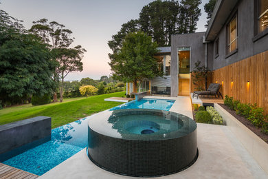 Стильный дизайн: большой бассейн-инфинити произвольной формы на заднем дворе в современном стиле с джакузи и покрытием из бетонных плит - последний тренд