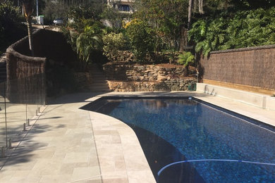 Diseño de piscina alargada moderna grande a medida en patio trasero con adoquines de hormigón