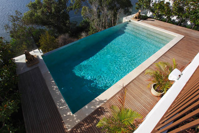 Cette photo montre une piscine hors-sol et avant tendance de taille moyenne et rectangle avec un point d'eau et une terrasse en bois.