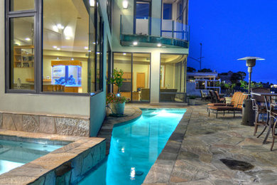 Example of a large trendy backyard stamped concrete and custom-shaped pool fountain design in Orange County