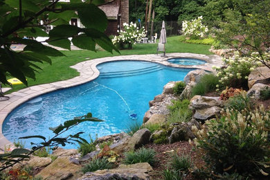 Modelo de piscina con fuente natural rústica grande a medida en patio trasero con adoquines de piedra natural