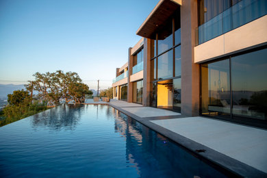 Modelo de piscina infinita contemporánea grande rectangular en patio trasero