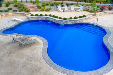 Diseño de piscina con fuente alargada tradicional renovada de tamaño medio a medida en patio trasero con adoquines de hormigón