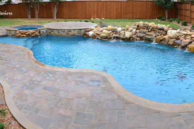 Example of a mid-sized trendy backyard stone and custom-shaped natural pool fountain design in Dallas