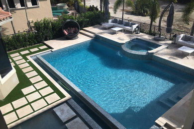 This is an example of a large contemporary back rectangular lengths hot tub in Miami with tiled flooring.