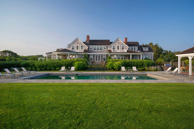 Photo of an expansive coastal back rectangular lengths swimming pool in Boston with a pool house and natural stone paving.