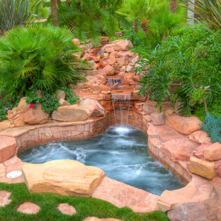 Foto di una grande piscina naturale tropicale personalizzata dietro casa con fontane e pavimentazioni in pietra naturale