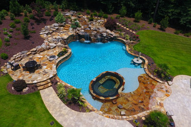 Hot tub - large rustic backyard concrete paver and custom-shaped natural hot tub idea in Atlanta