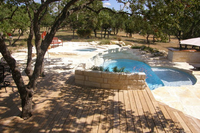 Diseño de piscinas y jacuzzis alargados de estilo americano grandes a medida en patio trasero con adoquines de piedra natural
