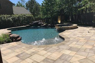 Hot tub - large tropical backyard concrete paver and custom-shaped hot tub idea in Houston