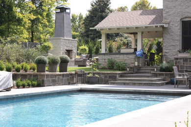 Bild på en pool på baksidan av huset, med naturstensplattor