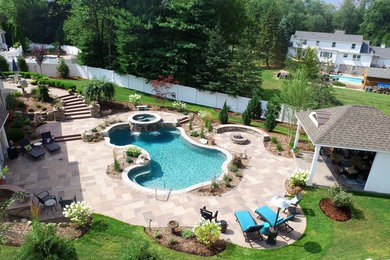 Modelo de piscinas y jacuzzis naturales clásicos grandes a medida en patio trasero con adoquines de piedra natural