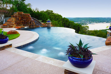 Large tuscan backyard concrete and custom-shaped infinity water slide photo in Austin