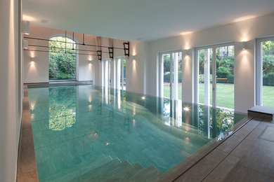 Großer Moderner Indoor-Pool in rechteckiger Form mit Natursteinplatten in Hamburg