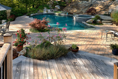 Immagine di una piscina naturale chic personalizzata di medie dimensioni e dietro casa con pavimentazioni in cemento e una vasca idromassaggio