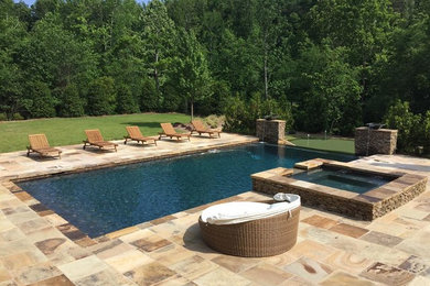 Example of a large mountain style backyard stone and custom-shaped infinity hot tub design in Birmingham