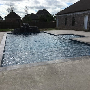 Ispirazione per una grande piscina naturale contemporanea rettangolare dietro casa con fontane e pedane