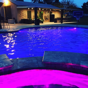 Immagine di una grande piscina naturale personalizzata dietro casa con una vasca idromassaggio e pedane