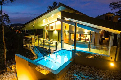 Foto på en stor funkis infinitypool längs med huset, med poolhus och naturstensplattor
