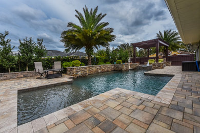 Großer Moderner Pool hinter dem Haus in individueller Form mit Wasserspiel und Natursteinplatten in Orlando