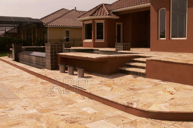 This is an example of a large rustic back custom shaped infinity hot tub in Orlando with natural stone paving.