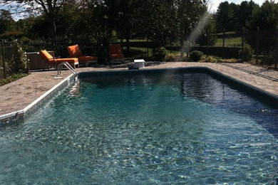 Diseño de piscina en forma de L en patio trasero con adoquines de piedra natural