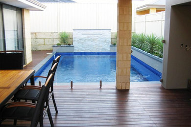 Modelo de piscina con fuente moderna pequeña rectangular en patio con entablado