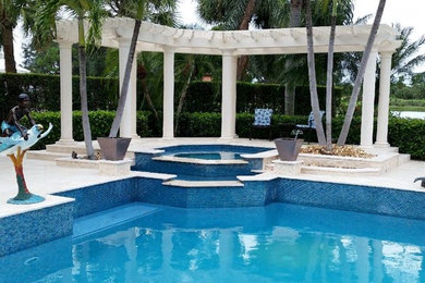 Идея дизайна: большой бассейн произвольной формы на заднем дворе в стиле неоклассика (современная классика) с фонтаном и покрытием из каменной брусчатки