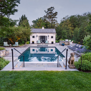 Photo of a large transitional backyard rectangular lap pool in DC Metro with a pool house and natural stone pavers.