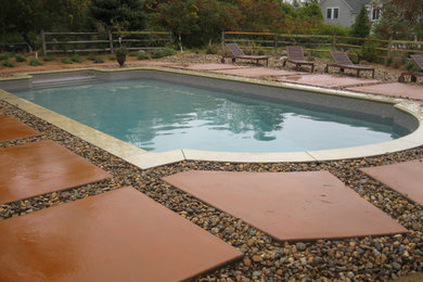 This is an example of a large back swimming pool in Boston with concrete paving.