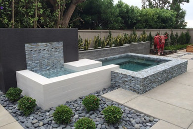 Ejemplo de piscina con fuente contemporánea a medida en patio trasero con suelo de baldosas