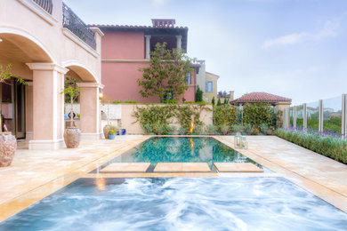Inspiration for a mid-sized contemporary backyard stone and rectangular infinity pool remodel in Orange County
