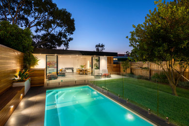 Diseño de casa de la piscina y piscina alargada contemporánea de tamaño medio rectangular en patio trasero con adoquines de piedra natural