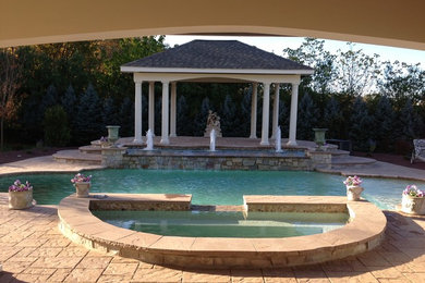 Imagen de piscina con fuente tradicional grande a medida en patio trasero con adoquines de hormigón