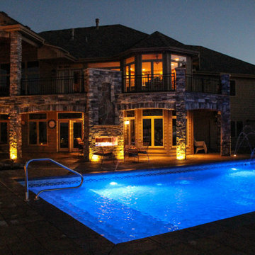 Nighttime Swimming Pool With Water Weirs and Fire Place