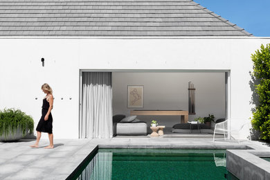 Inspiration för stora moderna anpassad pooler på baksidan av huset, med poolhus och naturstensplattor