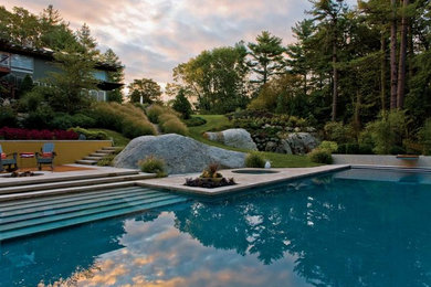 Design ideas for an expansive contemporary back custom shaped natural swimming pool in Boston with a water feature and concrete paving.