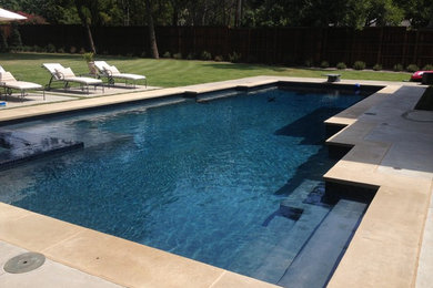 Foto de piscina alargada actual grande en forma de L en patio trasero con losas de hormigón
