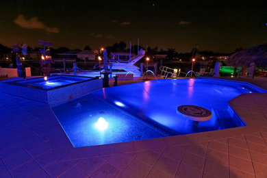 Modelo de piscina con fuente infinita moderna de tamaño medio a medida en patio trasero con adoquines de hormigón
