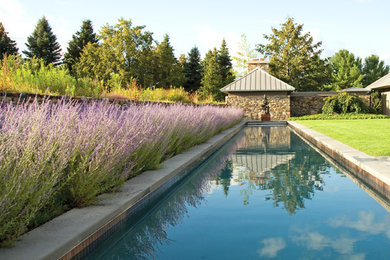 Foto de piscina alargada actual grande rectangular en patio trasero con losas de hormigón