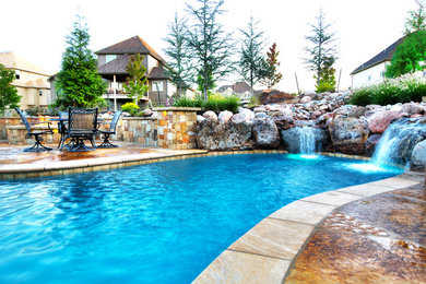 Foto de piscina con fuente natural actual grande a medida en patio trasero con adoquines de piedra natural
