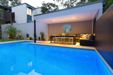 Foto de piscina tropical grande rectangular en patio trasero con adoquines de piedra natural