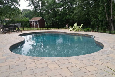 Diseño de piscinas y jacuzzis alargados de tamaño medio a medida en patio trasero con adoquines de ladrillo