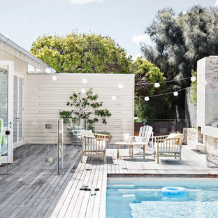 Immagine di una piscina costiera rettangolare di medie dimensioni e dietro casa con pedane