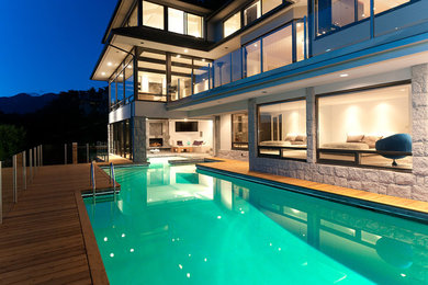 Photo of a large contemporary back custom shaped swimming pool in Vancouver with natural stone paving.