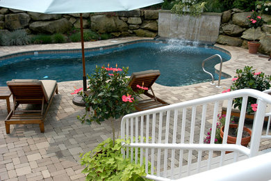 Foto de piscina con fuente natural actual de tamaño medio a medida en patio trasero con adoquines de ladrillo